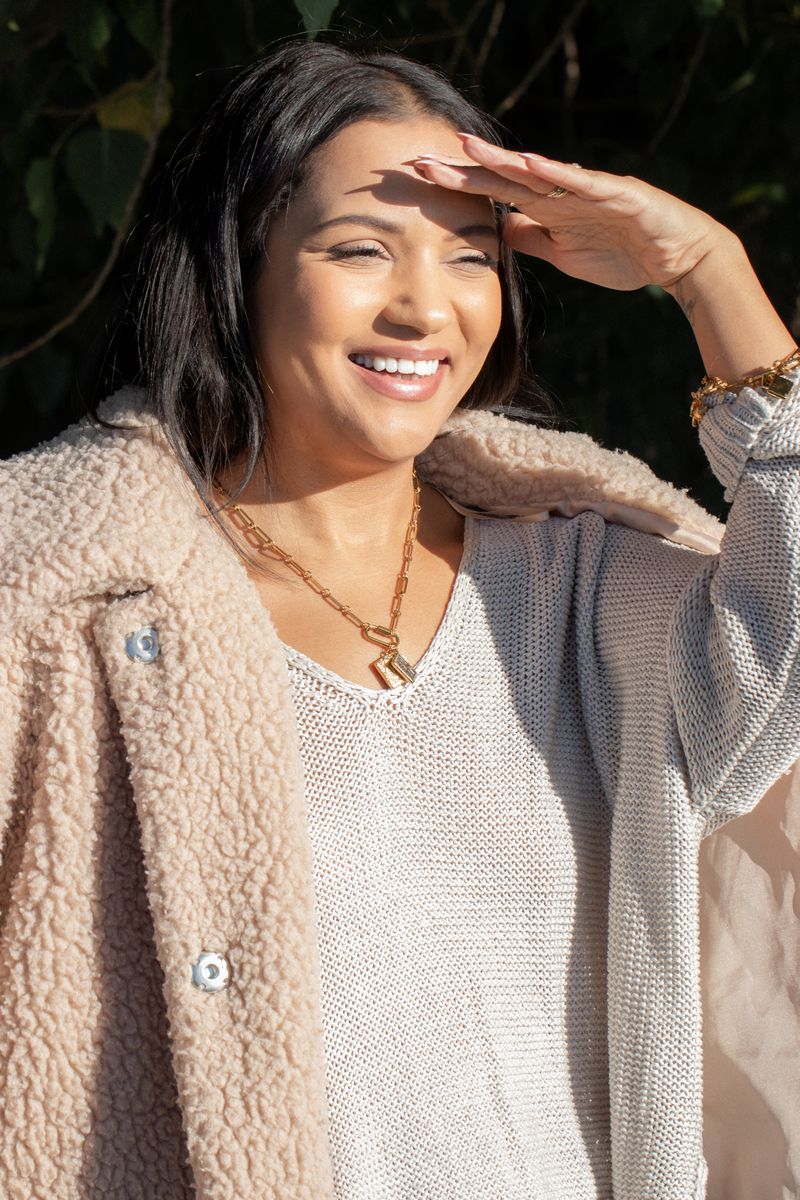 Laughing in a teddy coat by the canal, gold charm necklace