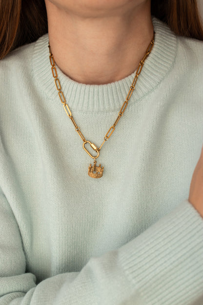 The Crown Charm worn on a gold paperclip chain
